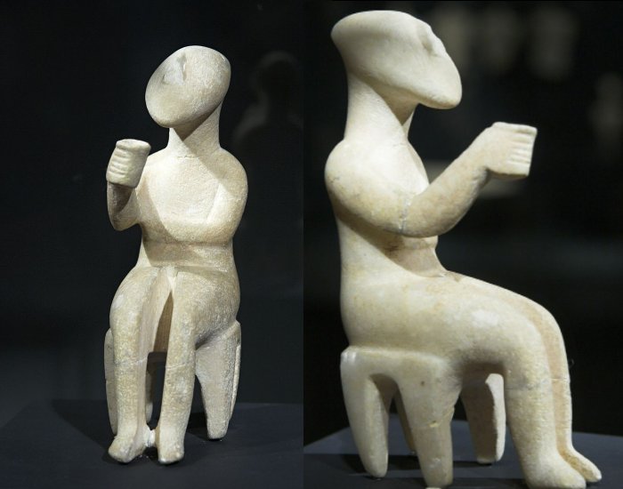 Left: Seated figure, a man holding a cup, early works of the Spedos variety, marble, height 15 cm, origin is unknown. Cycladic Early Bronze Age, EC II, 2800-2300 BC. Probably the man, because it is displayed in the plot. Sitting on a stool from a single piece of marble, his right hand with a cup about preparing to tribute or libation. Goulandris Foundation Museum of Cycladic Art (Athens) NG 286.; Right: Seated figure, a man holding a cup, early works of the Spedos variety, marble, height 15 cm, origin is unknown. Cycladic Early Bronze Age, EC II, 2800-2300 BC. Probably the man, because it is displayed in the plot. Sitting on a stool from a single piece of marble, his right hand with a cup about preparing to tribute or libation. Goulandris Foundation Museum of Cycladic Art, Athens. Goulandris Foundation Museum of Cycladic Art (Athens) NG 286.