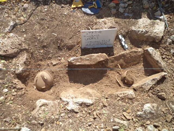 Maya cist burial with typical ceramic offerings - Plate covering the head of the deceased individual and cup placed likely with food. Credit: WSU