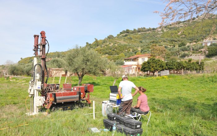  Use of the direct push system to examine the subsoil near the ancient temple at Kleidi to obtain evidence of changes to the coast and landscape. The hill in the background shows the remains of the walls of the ancient fortress of Samikon above Kleidi. Image credit: Vött group 