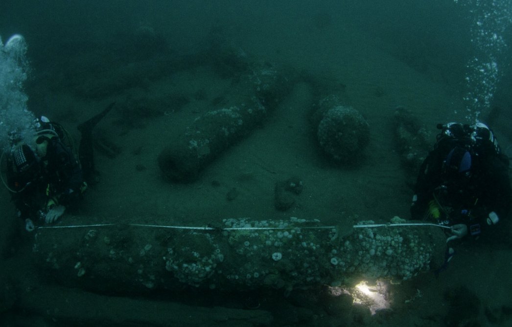 The Barnwell brothers measuring one of the ship's cannons. Credit: Norfolk Historic Shipwrecks